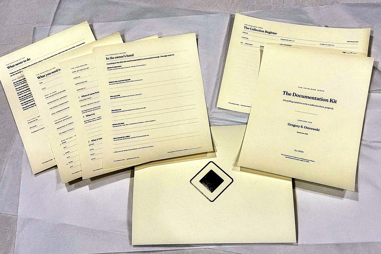 The six printed documents of the Documentation Kit fanned out on tissue &mdash; the cover sheet, the Collection Register and the card records, with a gold seal.